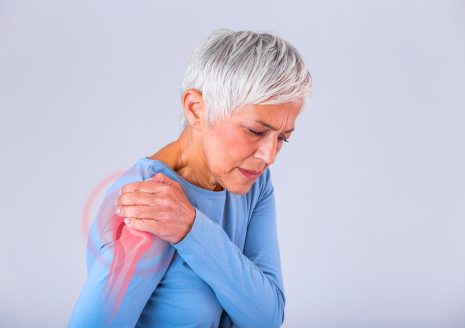 Woman experiencing shoulder pain with joint highlighted in red