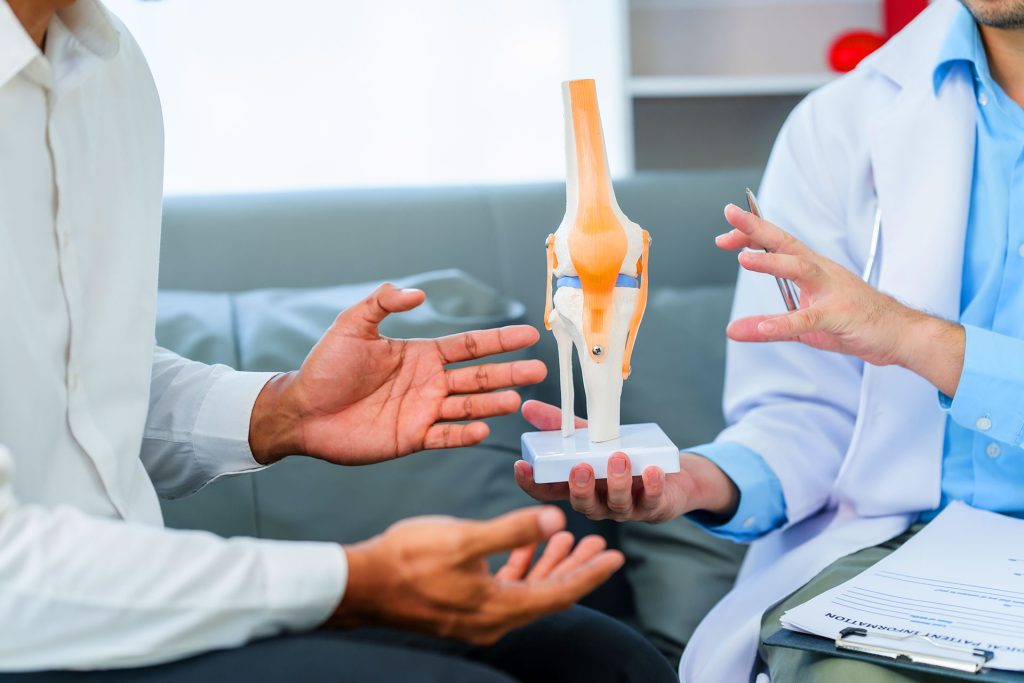 Doctor and patient discussing knee joint anatomical model