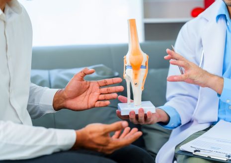 Doctor and patient discussing knee joint anatomical model