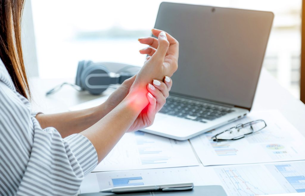 Wrist pain highlighted in red while typing at desk