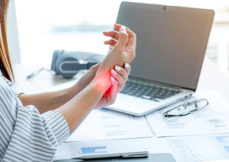 Wrist pain highlighted in red while typing at desk