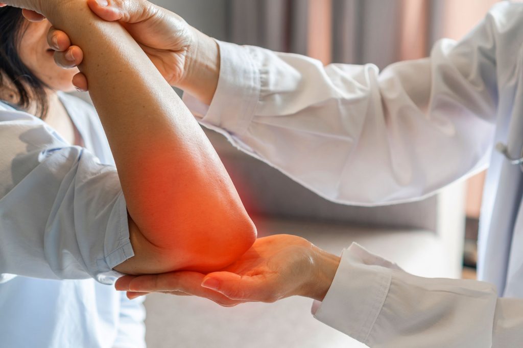 Doctor examining patient elbow with visible inflamed red pain area