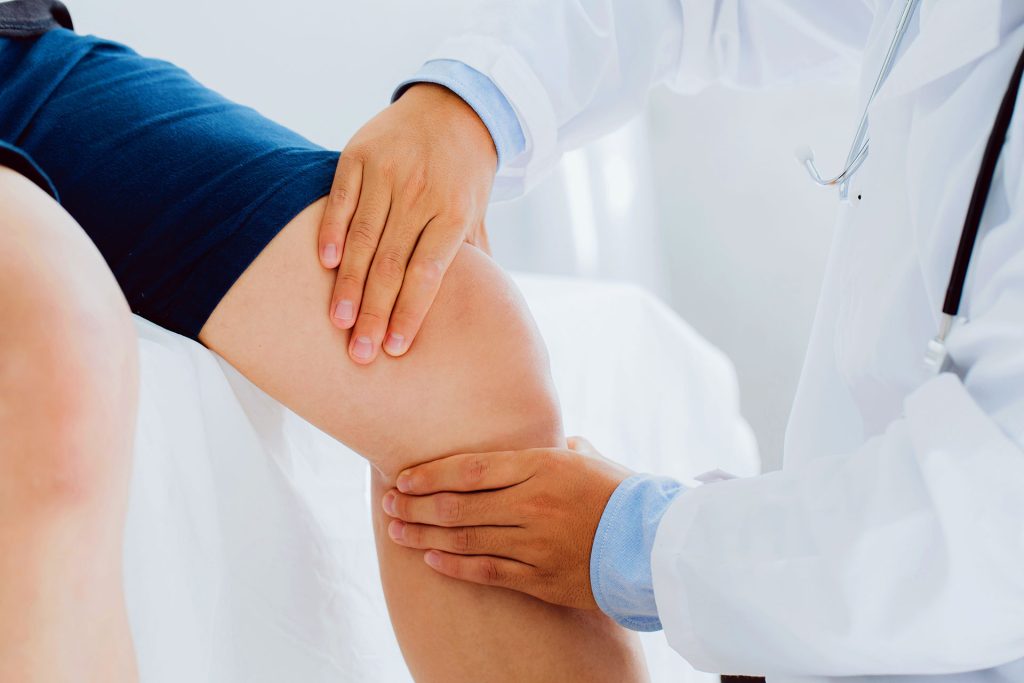 Doctor examining patient knee joint during pain management consultation