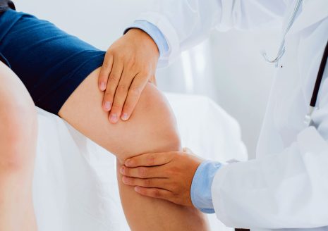 Doctor examining patient knee joint during pain management consultation